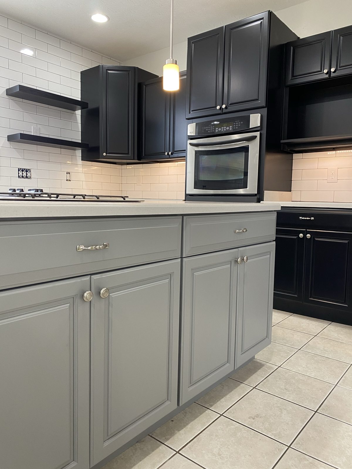 Black painted kitchen cabinets with gray island and stainless appliances