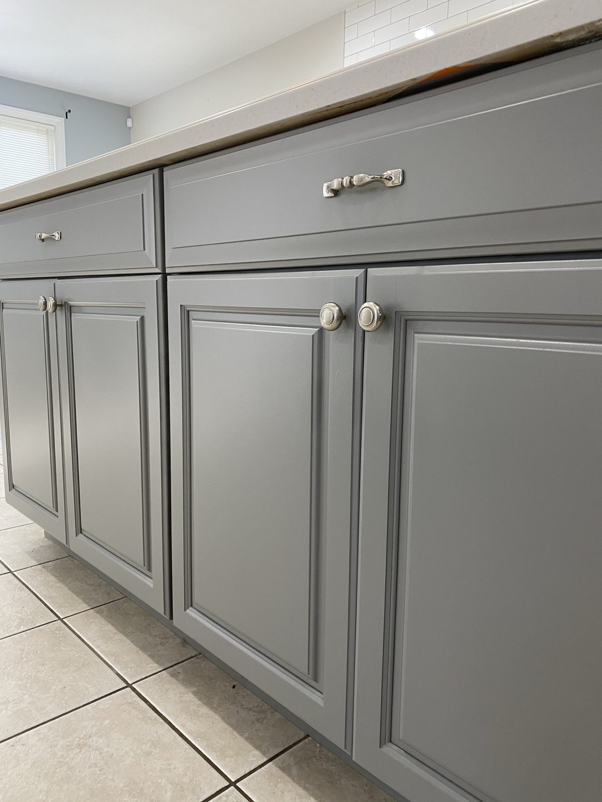 Gray painted lower kitchen cabinets with silver hardware