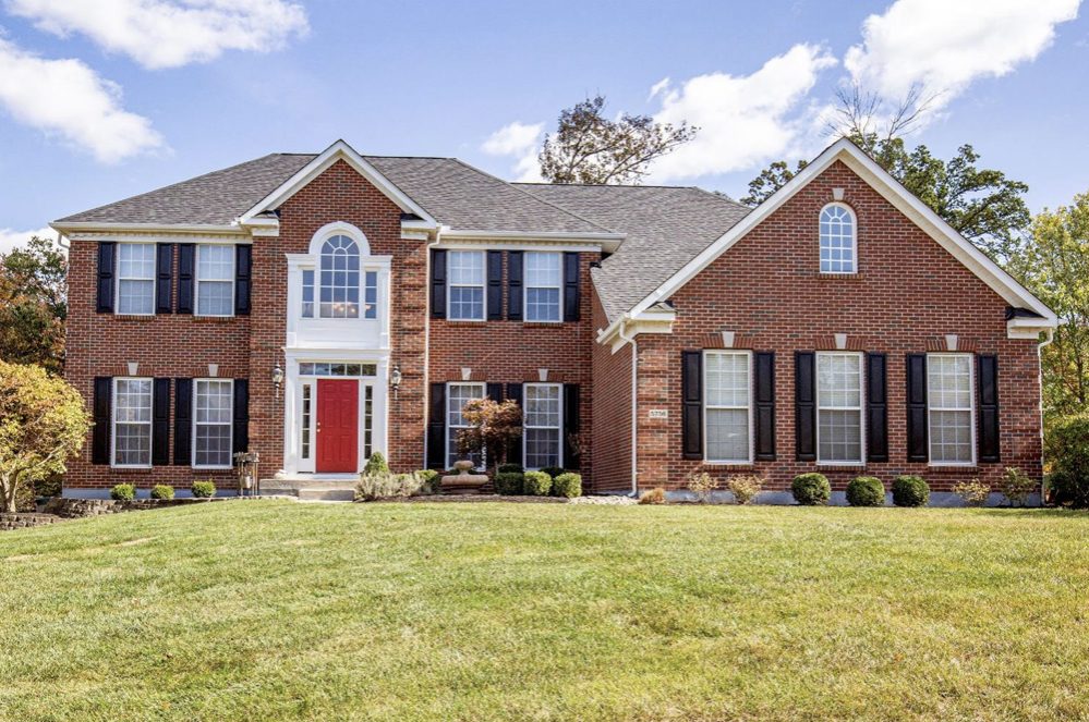 Freshly painted red brick two-story home with black shutters and white trim by Turner Painting