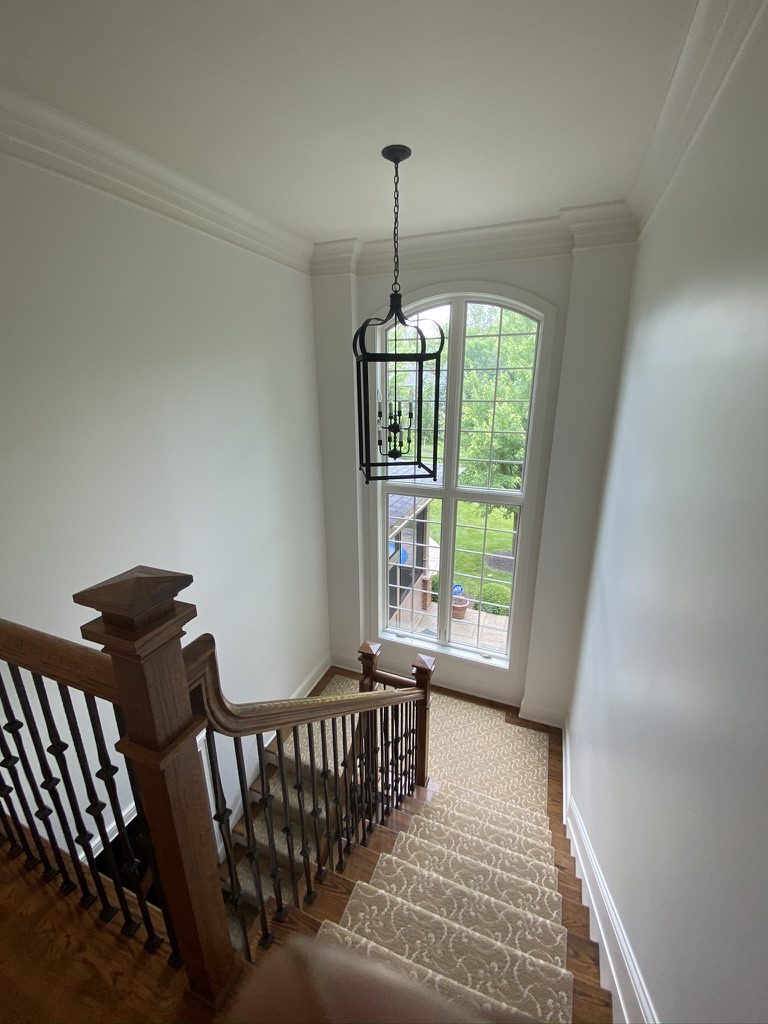 Freshly painted two-story stairwell with white trim and crown molding in Mason, OH