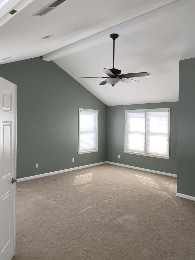 Bedroom painted sage green with white trim and vaulted ceiling in Monroe, OH