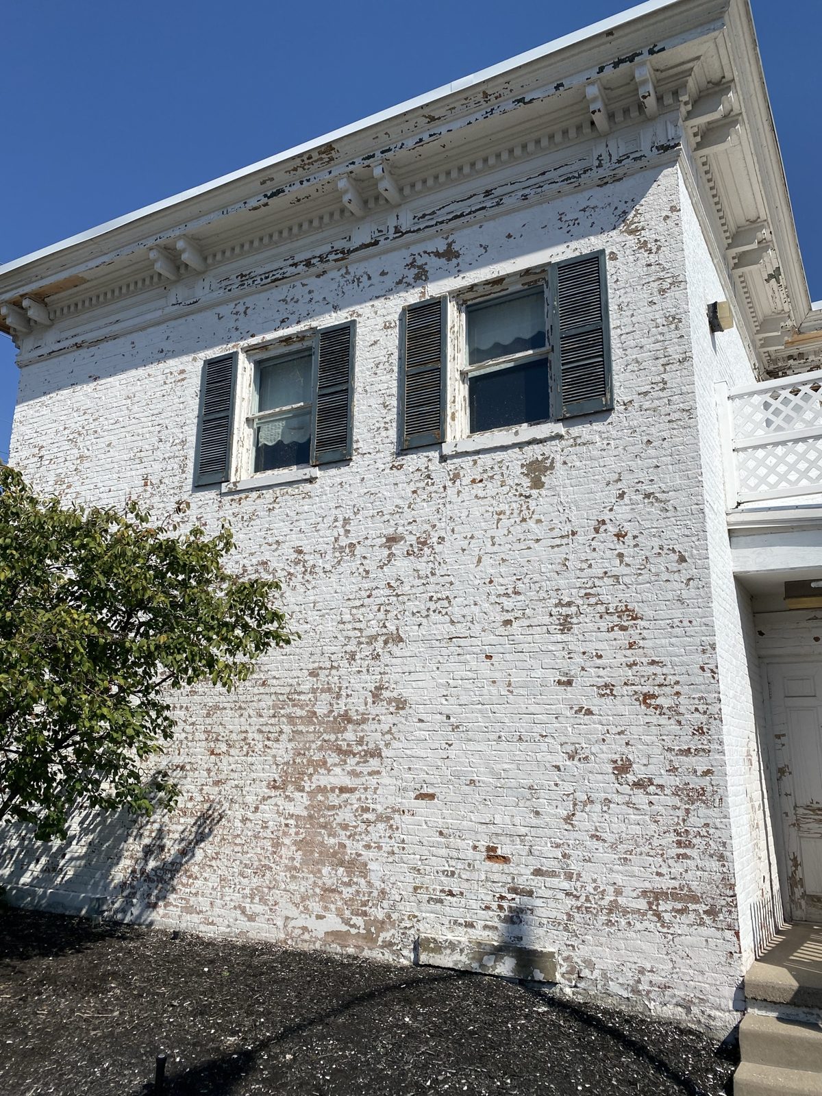 Peeling paint on a commercial brick building in Trenton, OH before repainting