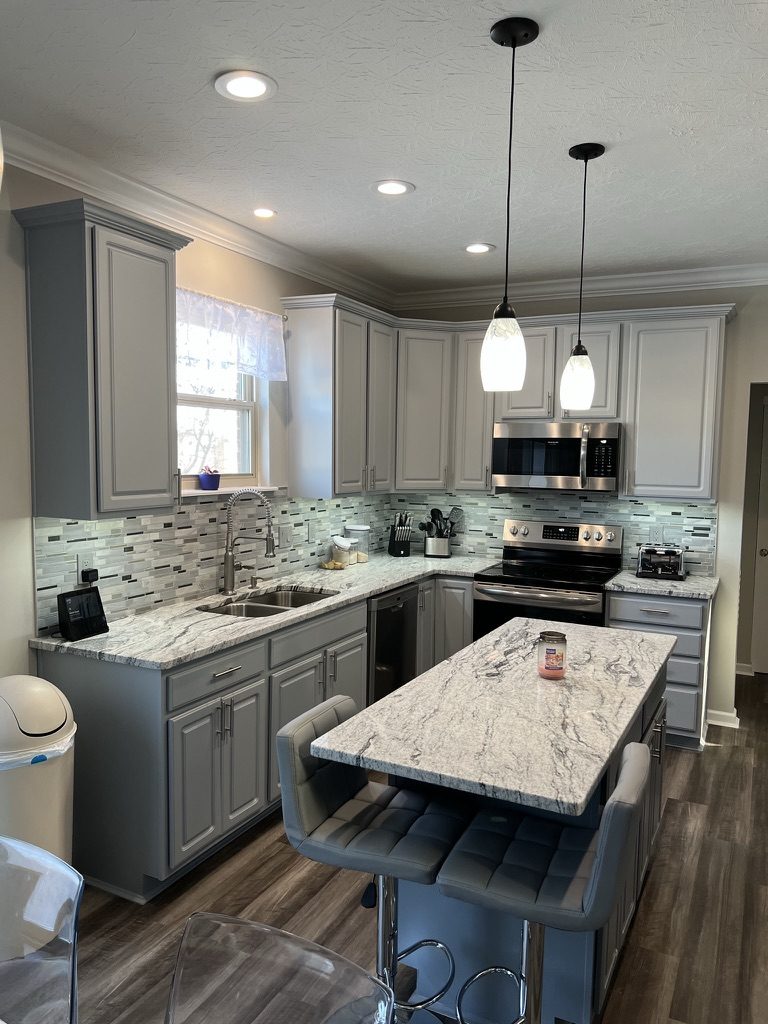 Light gray painted kitchen cabinets with white granite island in West Chester, OH